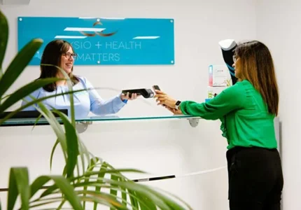 Customer pays by smartphone at Physio + Health Matters reception counter.